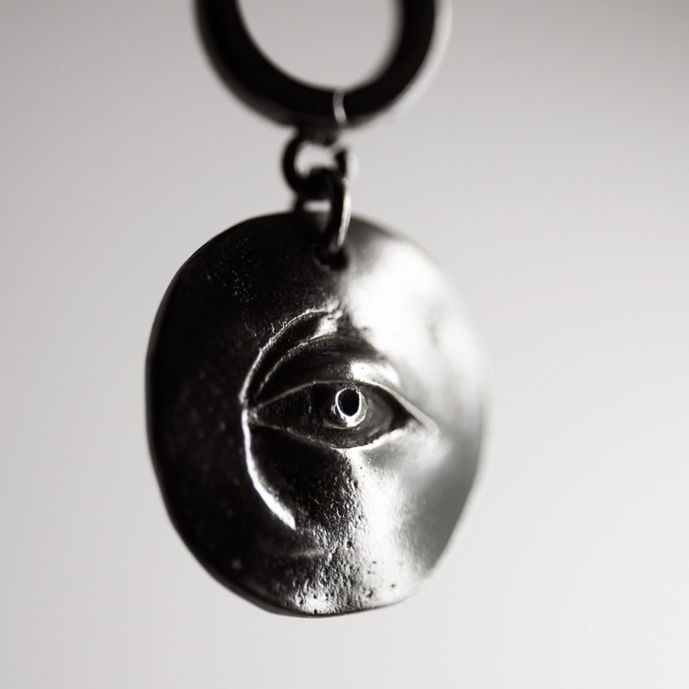 Close-up of Oculus eye earring - focus on sterling silver coin dangle with detailed eye relief