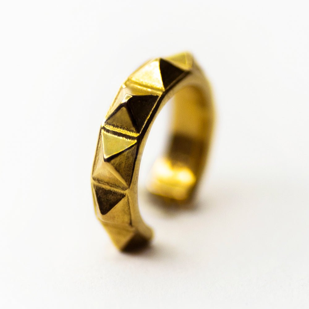 Pyramids ear cuff - miniature geometric ear cuff in gold-plated finish placed on white surface 