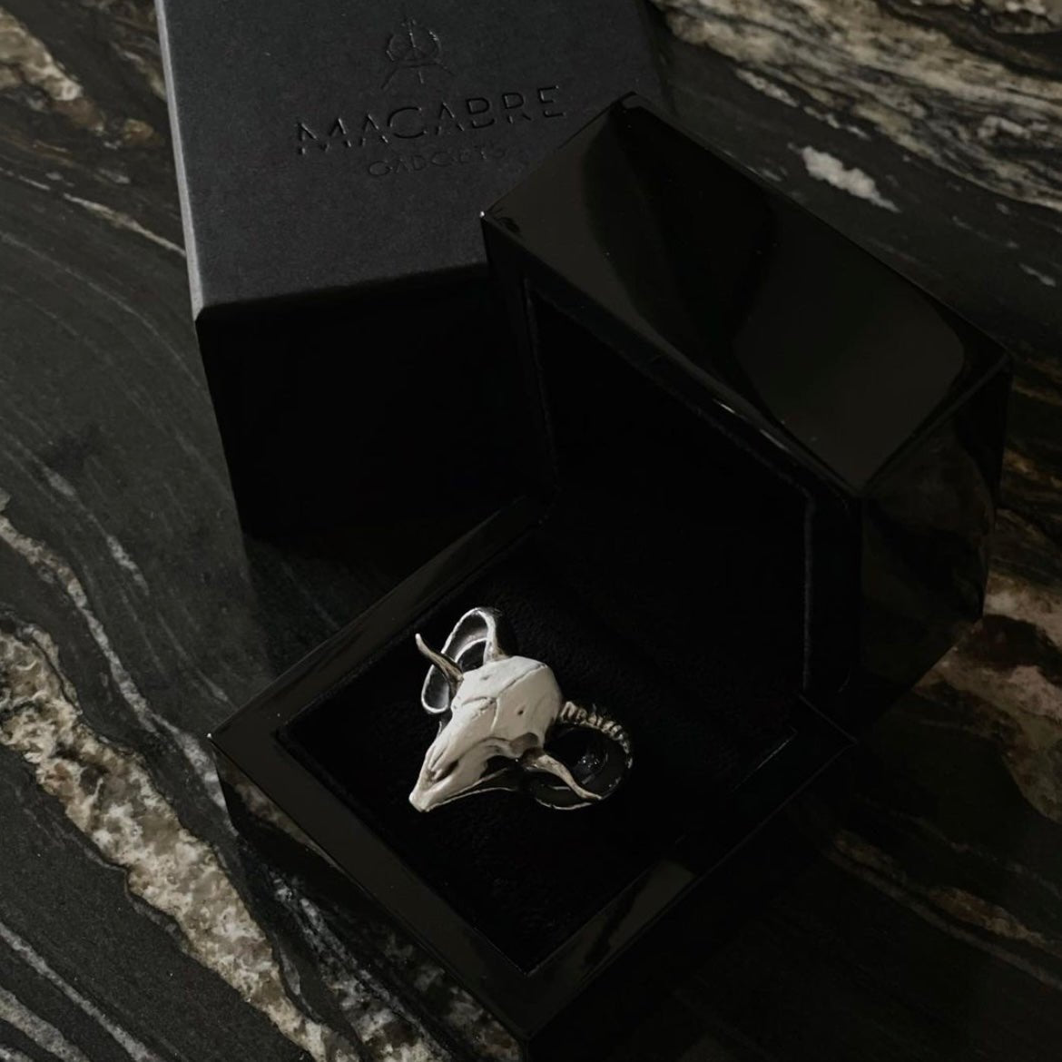 Ram ring in a glossy jewelry box, placed on a black marble surface