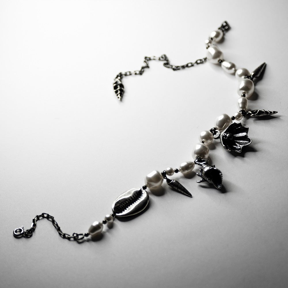 Silver Shells and Pearls choker on a white surface, anchor chain with diamond cut and lobster clasp are visible