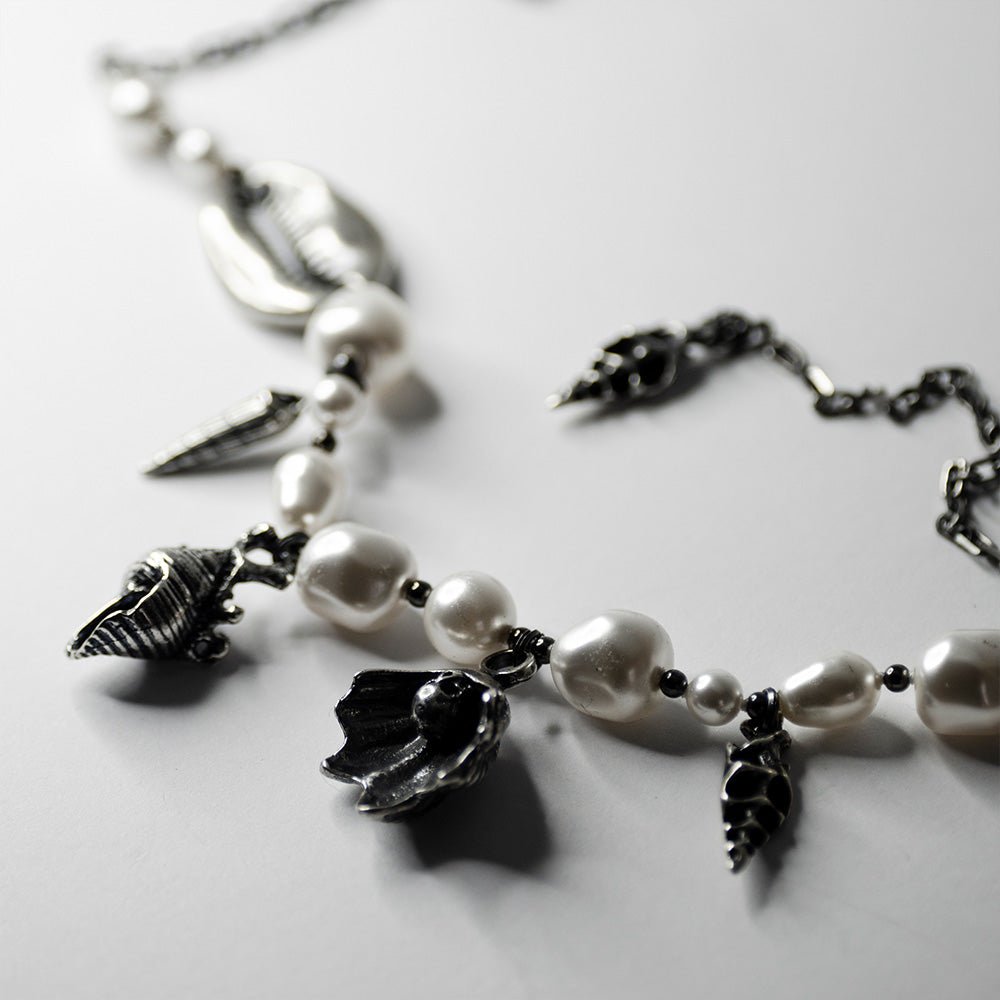 Silver Shells and Pearls choker by Macabre Gadgets placed on a white surface, sterling silver shells are visible