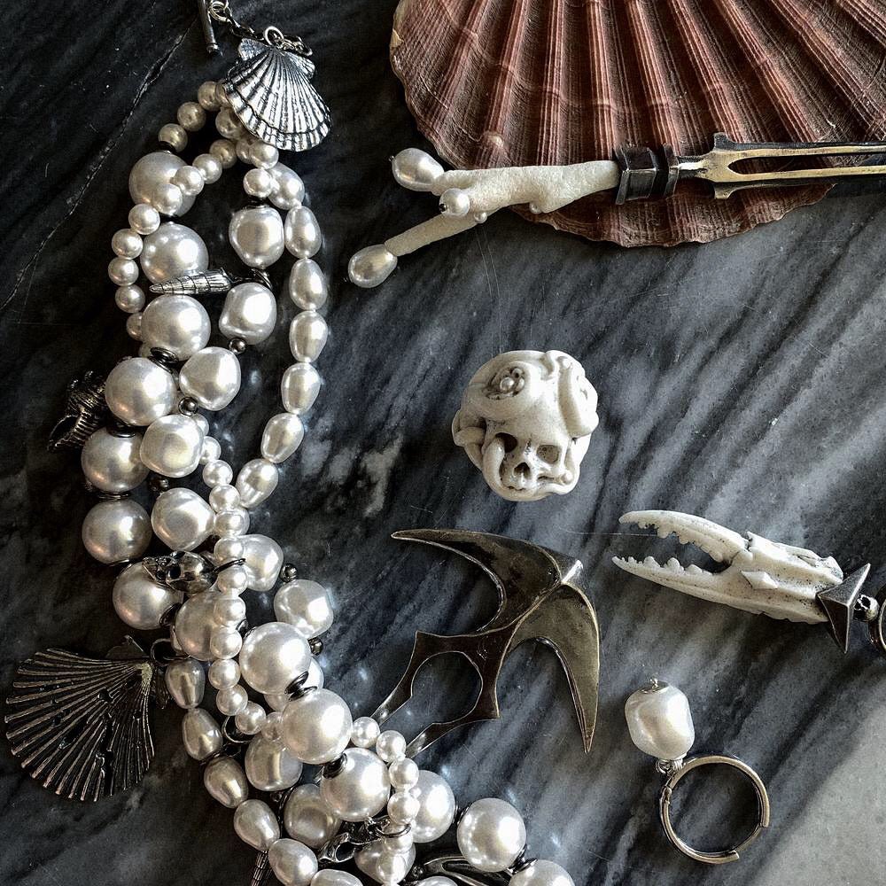 Siren Pearl Necklace placed on a grey marble surface, mixed with other Macabre Gadgets pieces