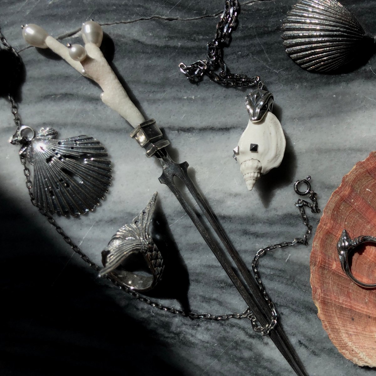 Siren ring along with other jewelry by Macabre Gadgets on grey marble surface
