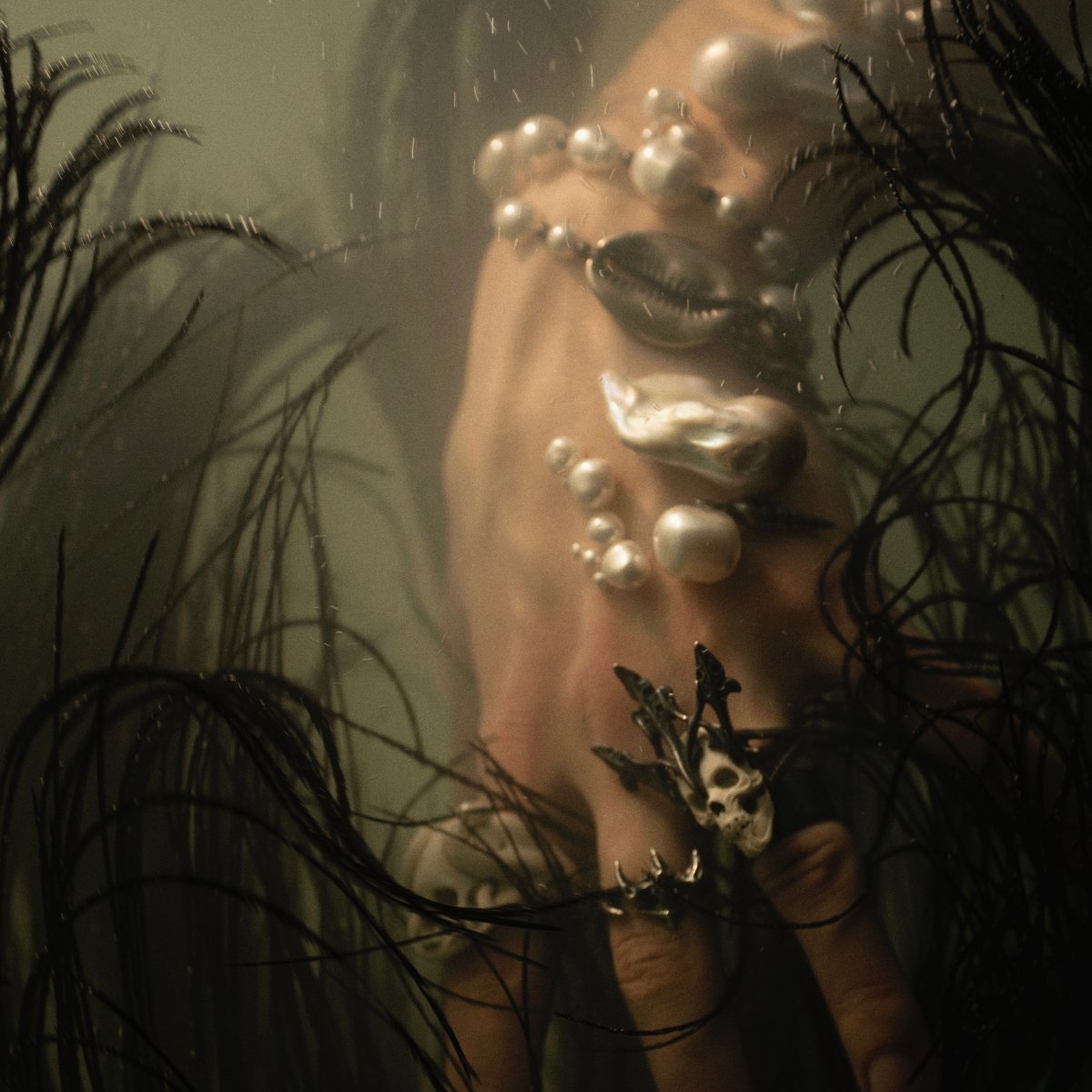 Vertebra ring on a hand of a model surrounded by black wavy seaweeds - underwater shot for Macabre Gadgets Siren campaign