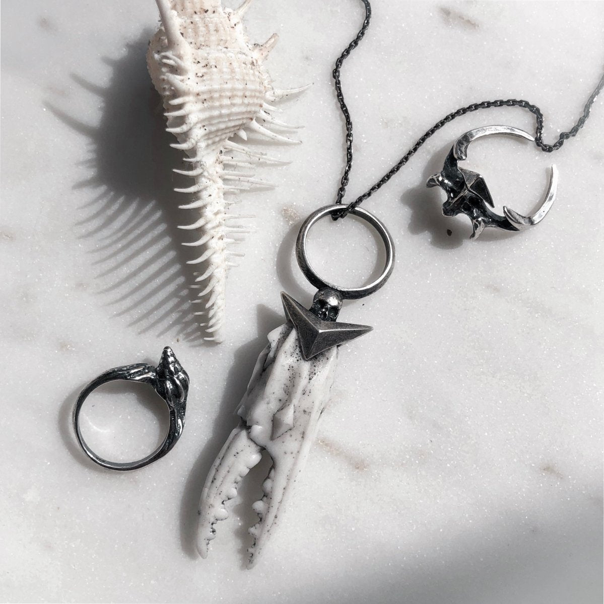 Vertebra ring together with other jewelry by Macabre Gadgets on white marble surface